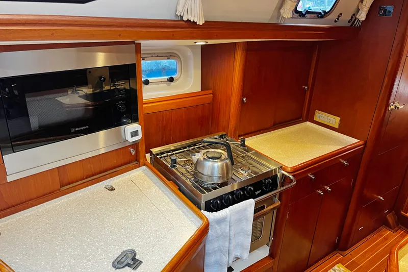 Slide: The Image of Kitchen area of a 1999 Oyster 53 Deck Saloon yacht with stove and microwave. - 25