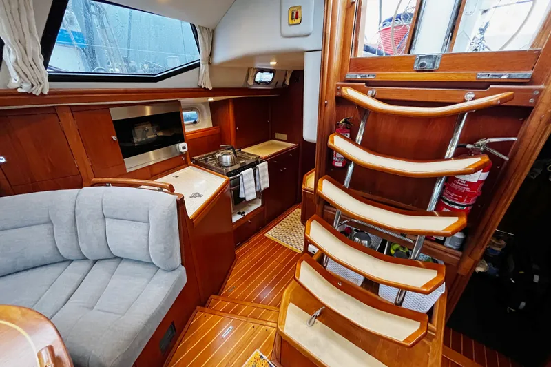 Slide: The Image of Interior of a 1999 Oyster 53 Deck Saloon yacht with wooden finishes and cozy seating. - 18
