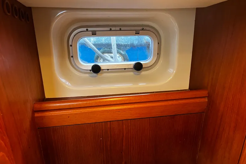 Slide: The Image of Interior view of 1999 Oyster 53 Deck Saloon, featuring a wooden panel and porthole. - 32