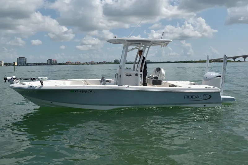 The Image of A 2023 Robalo 246 Cayman boat on calm water with a T-top and outboard motor. - 0