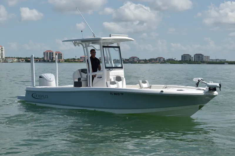 Slide: The Image of A modern 2023 Robalo 246 Cayman on calm waters. A man stands at the helm. - 4