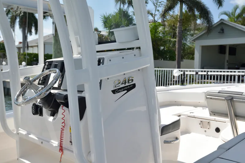 Slide: The Image of 2023 Robalo 246 Cayman boat interior with steering wheel and console, docked near palm trees. - 16