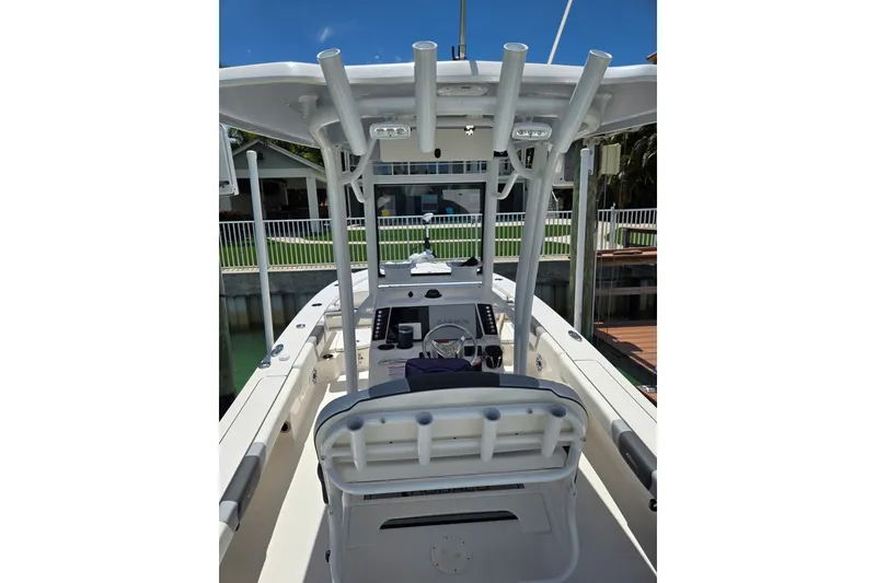 Slide: The Image of 2023 Robalo 246 Cayman boat interior with helm and seating, docked by a waterfront property. - 44