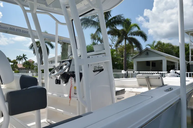Slide: The Image of 2023 Robalo 246 Cayman boat interior with steering wheel, palm trees, and sunny sky. - 20