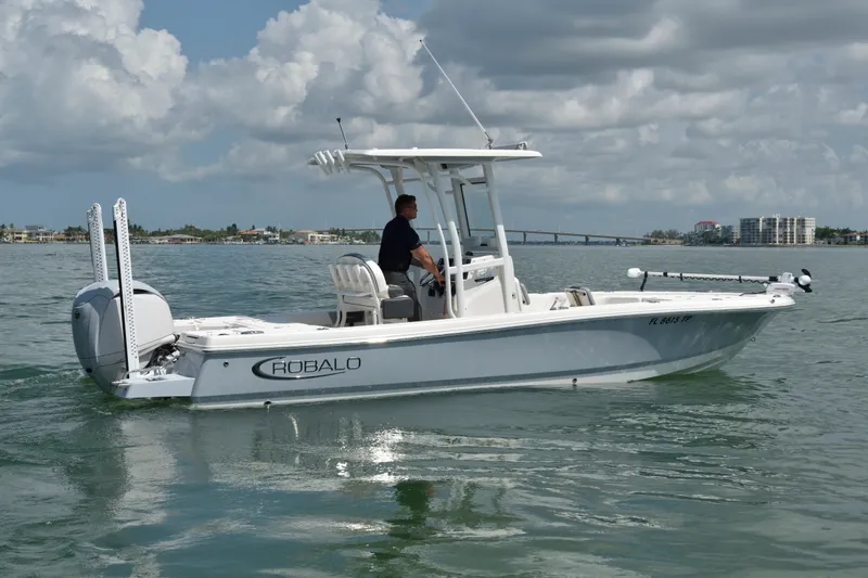 Slide: The Image of A white 2023 Robalo 246 Cayman boat on calm water with a driver on board. - 2