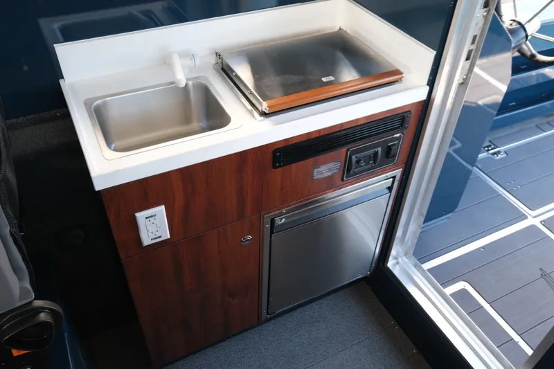 Slide: The Image of Compact kitchen area in 2026 Hewescraft 250 Pacific Explorer boat, featuring sink and appliances. - 19