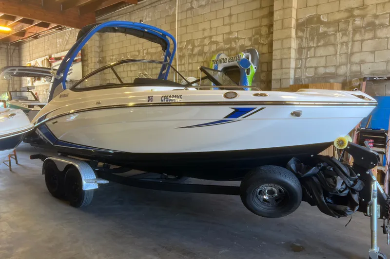 The Image of 2019 Yamaha Boats 212X in a garage, featuring sleek design and blue accents. - 0