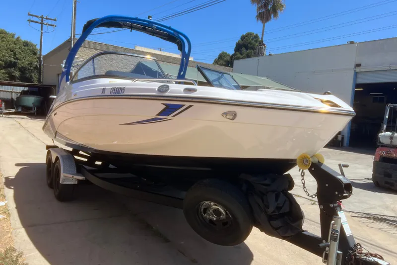 Slide: The Image of 2019 Yamaha Boats 212X on trailer, parked outdoors in sunny setting. - 19