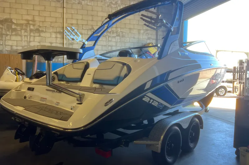 Slide: The Image of 2019 Yamaha Boats 212X in a garage, showcasing sleek design and dual axle trailer. - 2