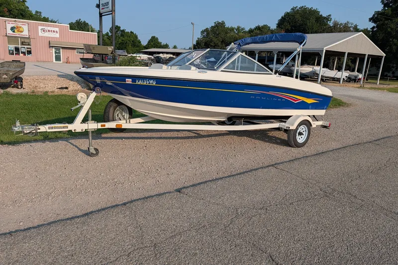 The Image of 2007 Bayliner 175 Bowrider on trailer, parked near a store and boat dealership. - 1