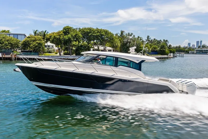 The Image of 2024 Tiara 48 LE luxury yacht cruising on a sunny day in a scenic waterway. - 0