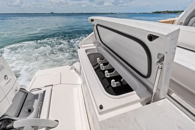 Slide: The Image of 2024 Tiara 48 LE boat with open storage compartment, ocean view in background. - 24