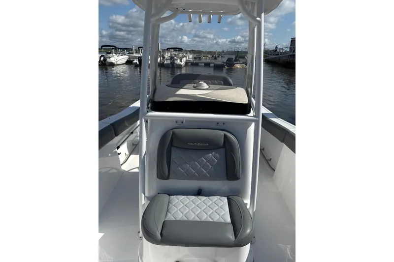 Slide: The Image of 2024 NauticStar 222L Offshore boat interior with cushioned seating at marina. - 4