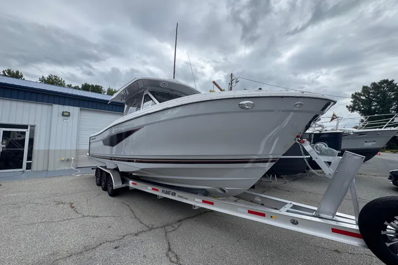 Slide: The Image of 2026 Solara S-310 CW boat on trailer, parked outside a building under cloudy skies. - 2