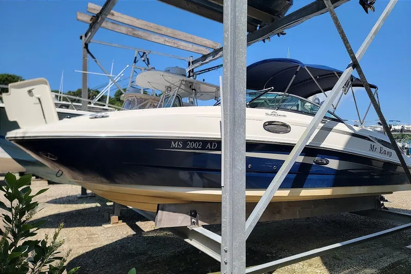 Slide: The Image of 2012 Sea Ray 260 Sundeck boat on a metal rack, blue and white exterior. - 20