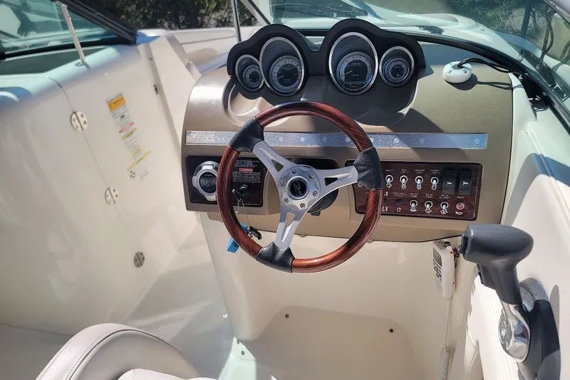 Slide: The Image of 2012 Sea Ray 260 Sundeck dashboard with wood-accented steering wheel and control panel. - 17
