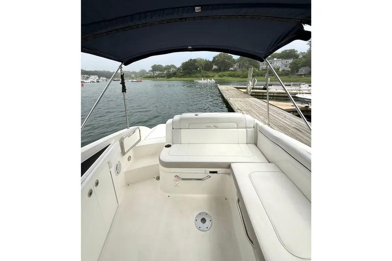 Slide: The Image of 2012 Sea Ray 260 Sundeck boat interior with white seating, docked by a scenic waterfront. - 13