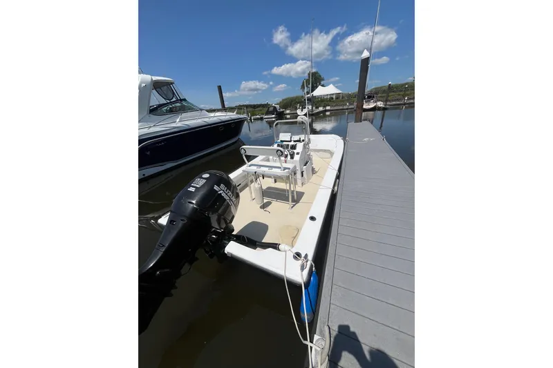 Slide: The Image of 2006 Twin Vee 19 BayCat boat docked, featuring a Suzuki outboard motor. - 2