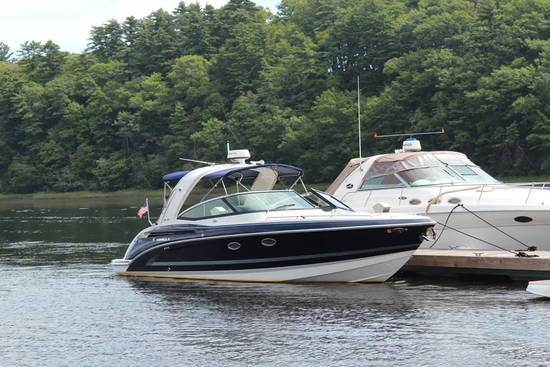 The Image of 2017 Formula 330 Crossover Bowrider docked on a serene lake with lush forest backdrop. - 0