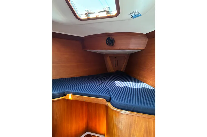 Slide: The Image of Cozy cabin interior of 1996 Freedom 35 sailboat with striped bedding and wooden finish. - 13