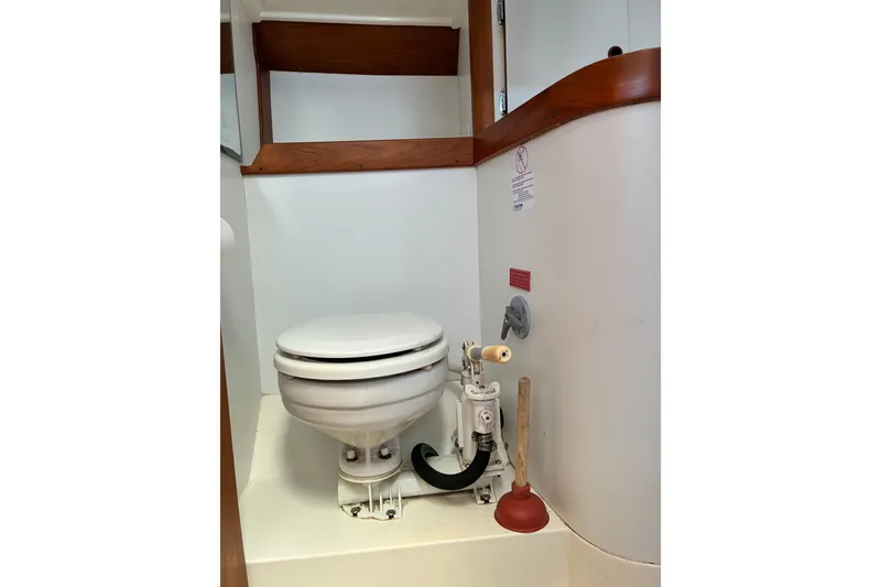 Slide: The Image of 1996 Freedom 35 boat bathroom with toilet and plunger, featuring wooden accents. - 21