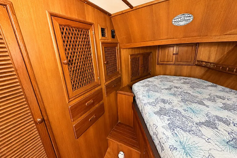 Slide: The Image of 1986 Marine Trader Labelle cabin interior with wooden cabinetry and patterned bedding. - 20