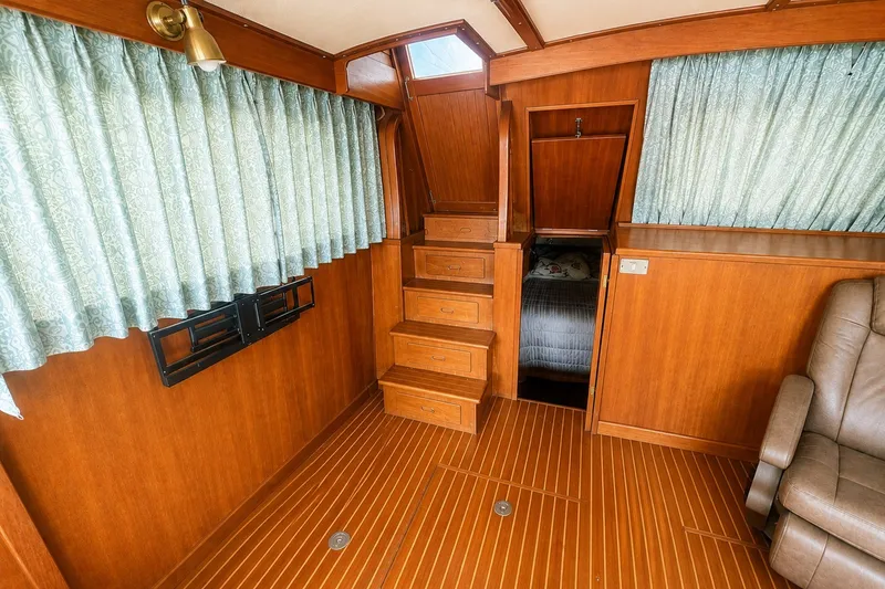 Slide: The Image of 1986 Marine Trader Labelle interior with wooden stairs, curtains, and seating. - 11