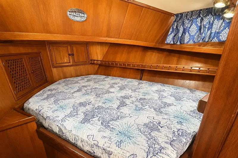 Slide: The Image of Cozy cabin interior of 1986 Marine Trader Labelle with nautical-themed bedding and wooden finish. - 19