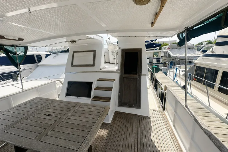 Slide: The Image of 1986 Marine Trader Labelle yacht deck with wooden table and docked boats. - 4