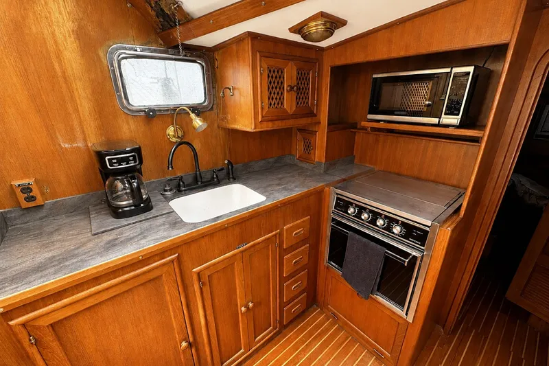 Slide: The Image of 1986 Marine Trader Labelle yacht kitchen with wood cabinetry, sink, stove, and microwave. - 15