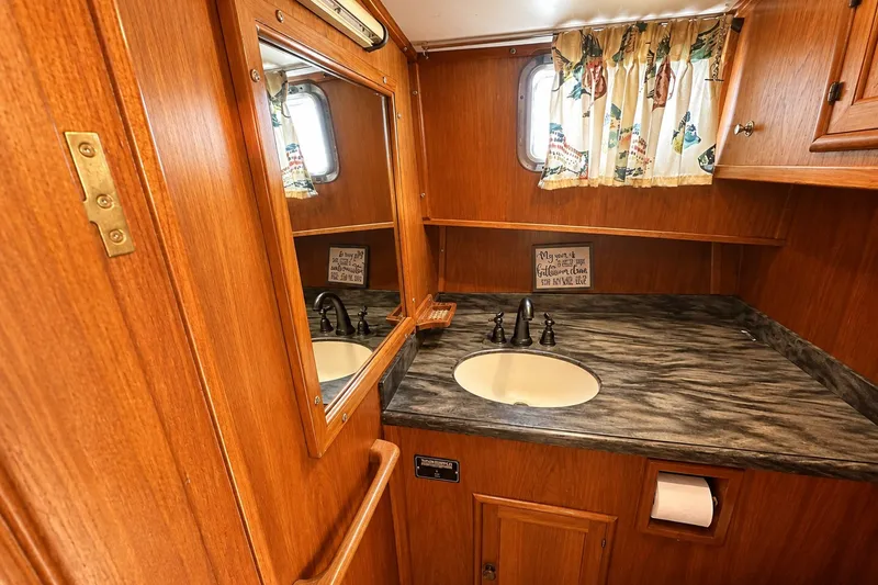 Slide: The Image of 1986 Marine Trader Labelle bathroom with wood paneling, mirror, and marble countertop. - 22