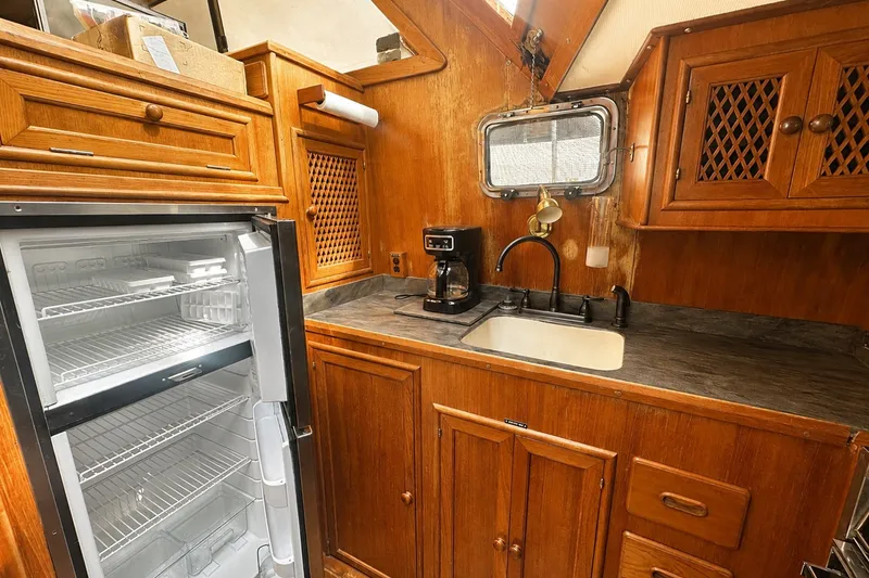 Slide: The Image of 1986 Marine Trader Labelle kitchen with wooden cabinets, sink, and open fridge. - 14