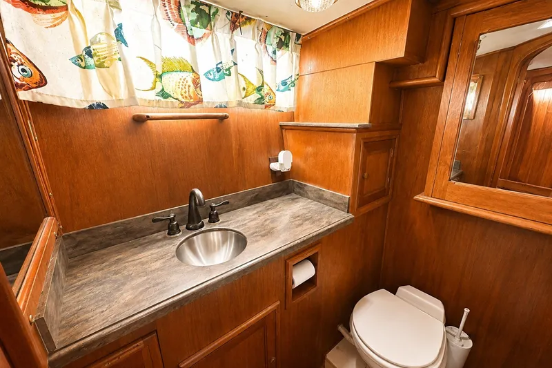 Slide: The Image of 1986 Marine Trader Labelle bathroom with wood paneling, fish-patterned curtains, and modern fixtures. - 28