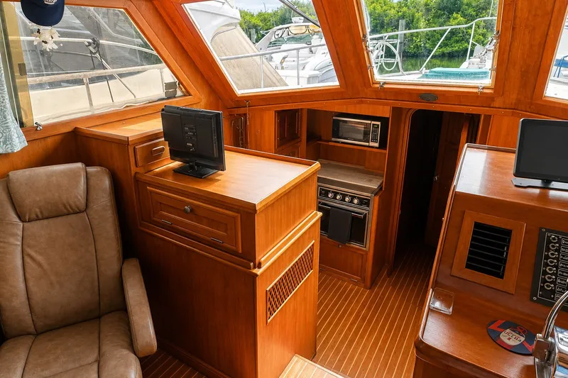 Slide: The Image of 1986 Marine Trader Labelle yacht interior with wood paneling, seating, and kitchen appliances. - 10