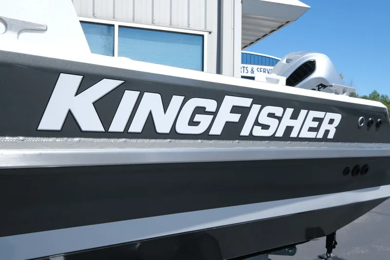 Slide: The Image of 2026 KingFisher 23 XAC boat exterior with bold branding, parked outside a service center. - 19