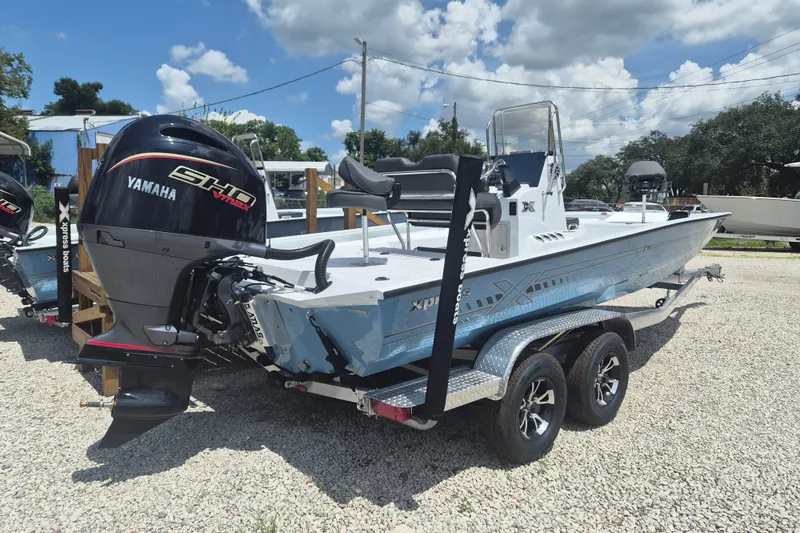 Slide: The Image of 2026 Xpress H22 Bay boat with Yamaha engine on a trailer, parked outdoors. - 2