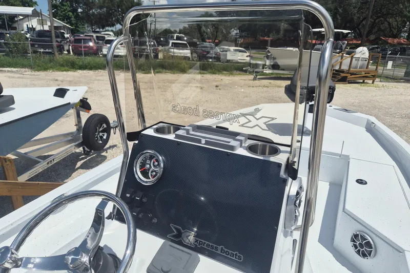 Slide: The Image of 2026 Xpress H22 Bay boat dashboard with steering wheel and gauge, parked outdoors. - 15