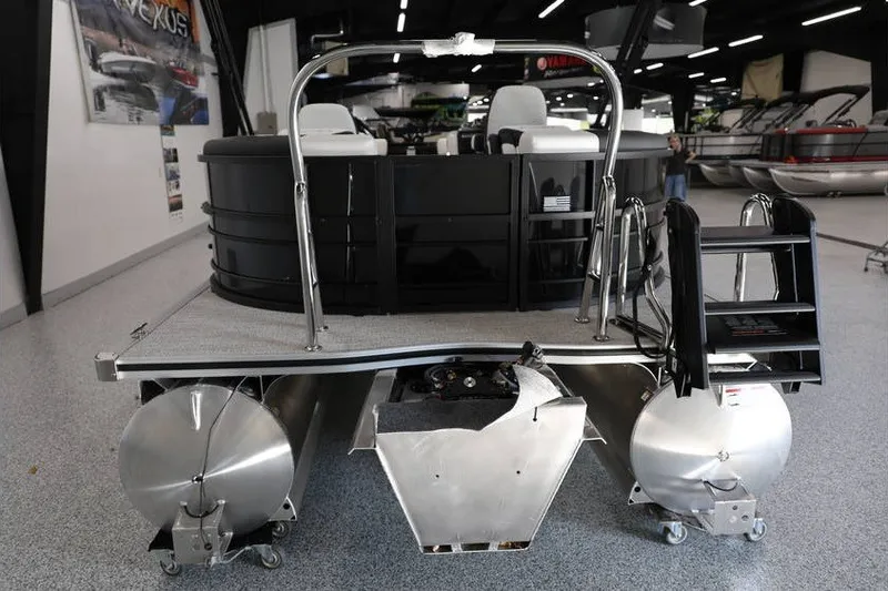 Slide: The Image of 2026 South Bay 224 RS Tritoon boat displayed in showroom, rear view with seating and pontoons. - 10