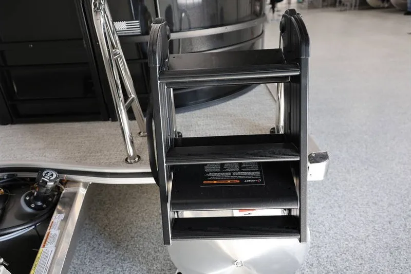 Slide: The Image of Boarding ladder on 2026 South Bay 224 RS Tritoon boat, shown in a showroom setting. - 29