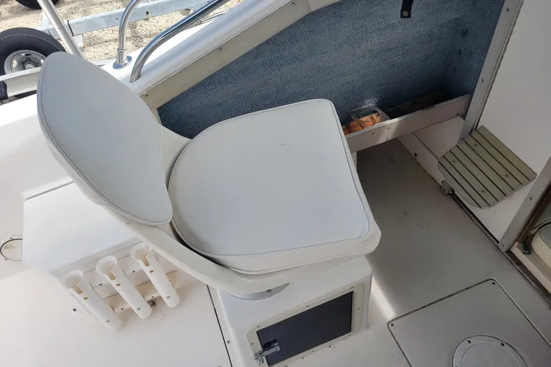Slide: The Image of 1990 Grady-White Overnighter 204 boat interior with white seating and storage compartments. - 13