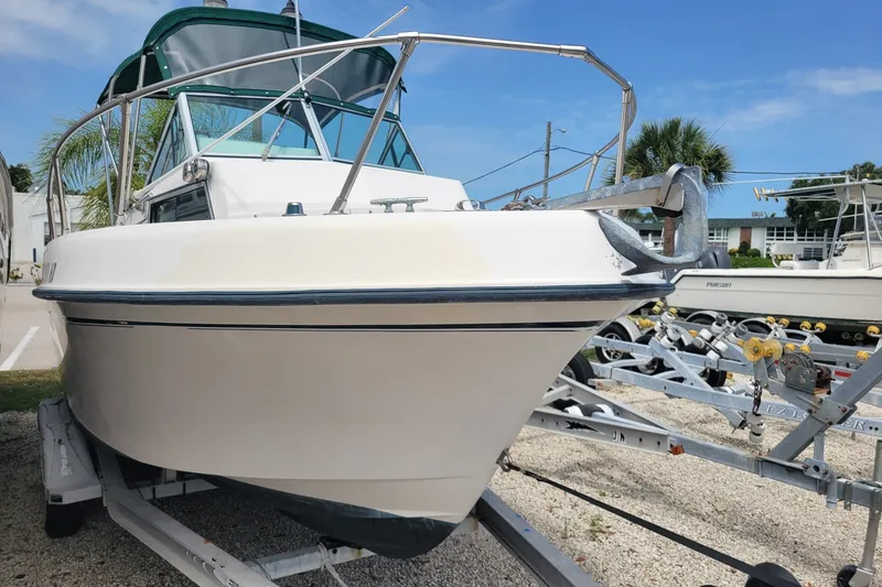 Slide: The Image of 1990 Grady-White Overnighter 204 boat on trailer, parked outdoors under blue sky. - 2