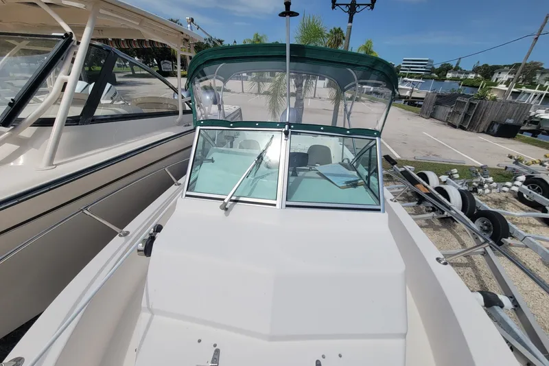 Slide: The Image of 1990 Grady-White Overnighter 204 boat with green canopy, docked outdoors. - 18