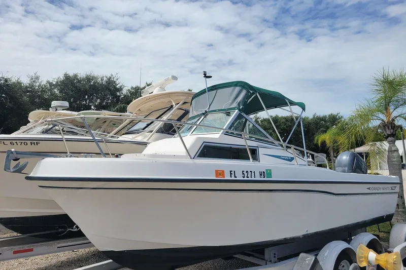The Image of 1990 Grady-White Overnighter 204 boat on trailer, with green canopy, parked outdoors. - 1