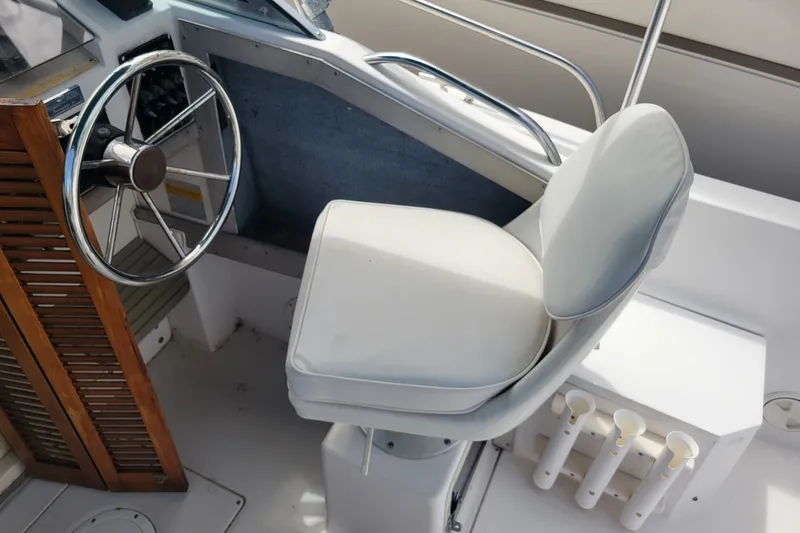 Slide: The Image of 1990 Grady-White Overnighter 204 boat helm with steering wheel and cushioned seat. - 12