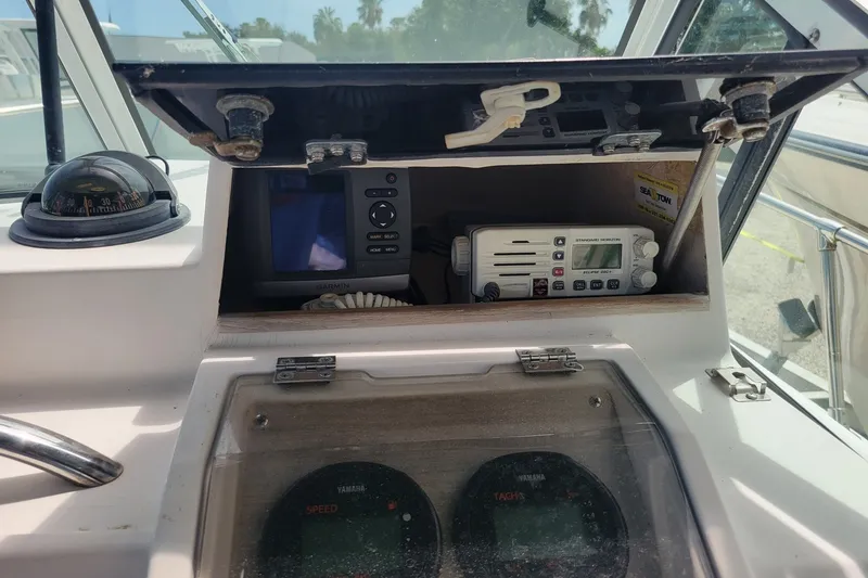 Slide: The Image of 1990 Grady-White Overnighter 204 boat dashboard with compass, Garmin GPS, and radio equipment. - 16