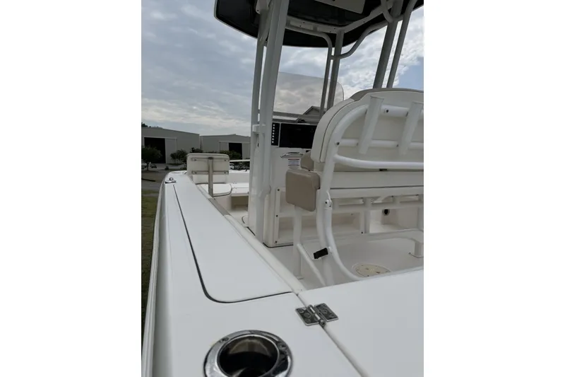 Slide: The Image of 2022 Robalo 226 Cayman boat interior with seating and console, under cloudy sky. - 7
