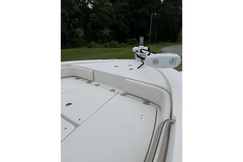 Slide: The Image of 2022 Robalo 226 Cayman boat deck with trolling motor, surrounded by lush greenery. - 2