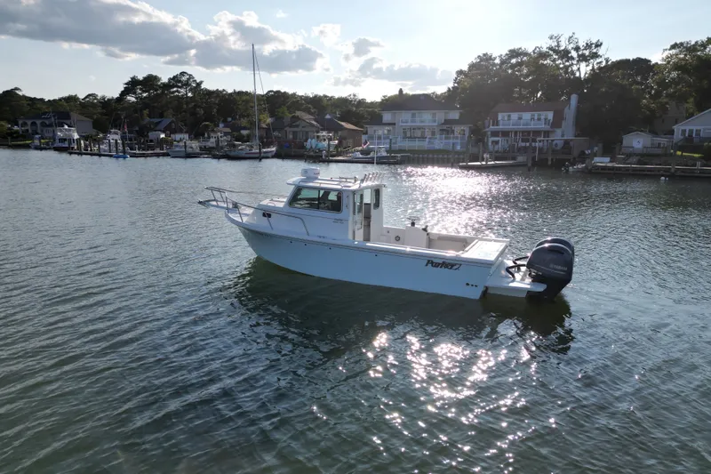 Slide: The Image of 2021 Parker 2520 XLD Sport Cabin boat on calm water near residential docks. - 4