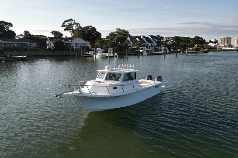 Slide: The Image of 2021 Parker 2520 XLD Sport Cabin boat on calm water near residential docks. - 17