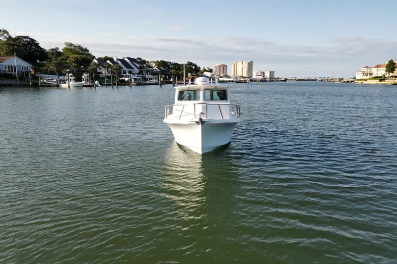 Slide: The Image of 2021 Parker 2520 XLD Sport Cabin boat on calm water near residential shoreline. - 2